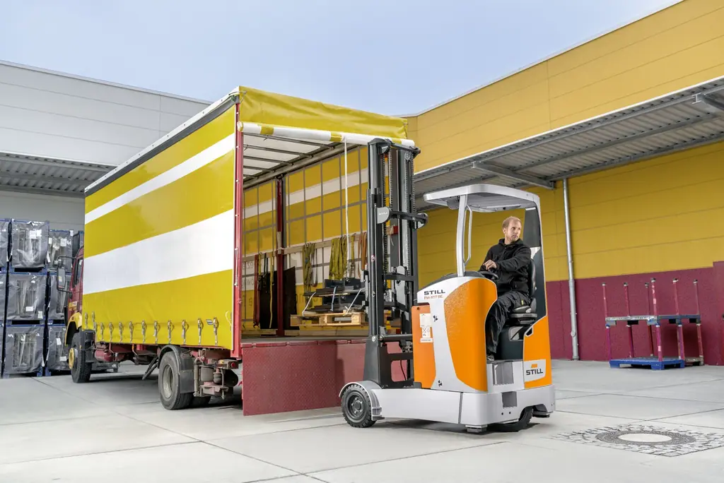Lojistik tesisinde tenteli bir kamyonun yan tarafında yükleme/boşaltma yapan STILL FM-X SE reach truck