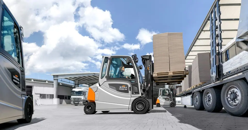 STILL RX 60-30 akülü forklift, açık alanda tenteli kamyona karton yüklü palet yüklerken