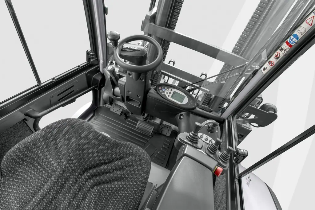 STILL RX 60-80 sürücü kabininin içi: direksiyon, ekran, pedallar ve kol dayamalı çok kollu mini-lever kumanda