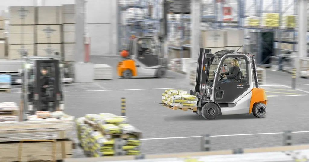 Yapı malzemesi deposunda torba yüklü paleti taşıyan kabinli STILL RX 70-25 forklift