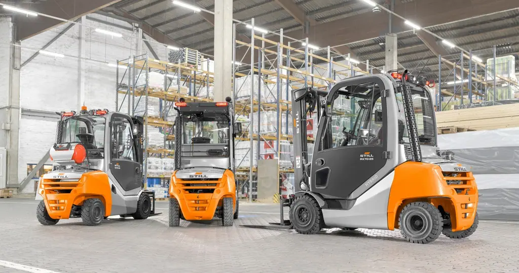 Raflı bir depoda yan yana duran üç STILL RX 70 serisi forklift