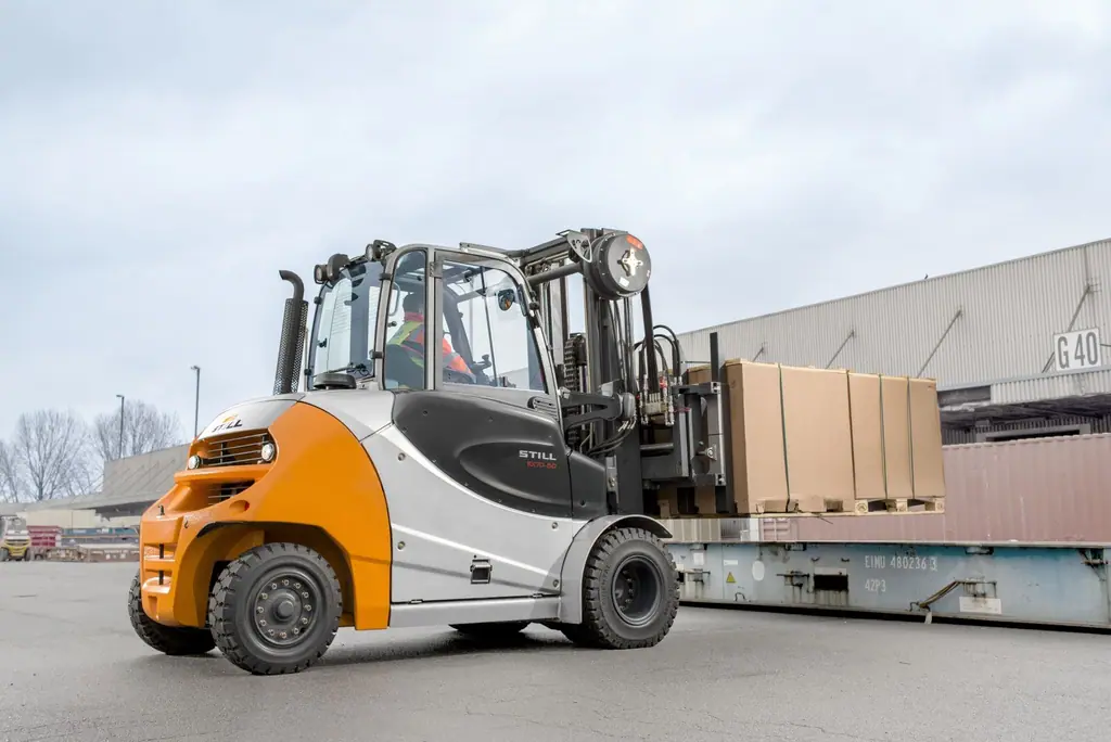 STILL RX 70-80 dizel forklift yük terminalinde vagon yanında koli yüklü palet taşırken