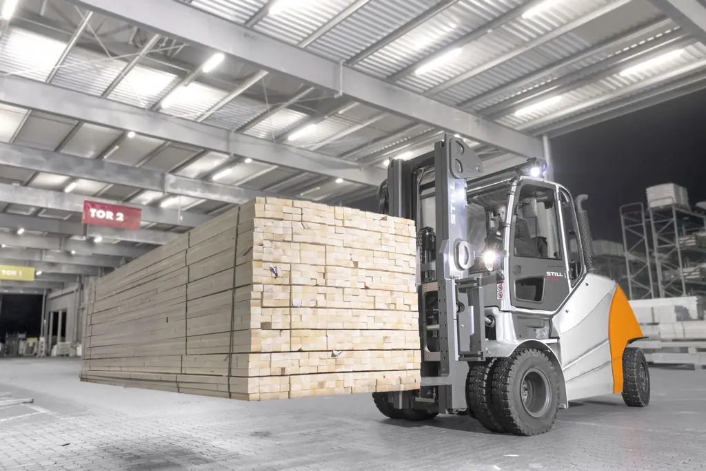 STILL RX 70-80 dizel forklift kereste paketi taşırken, üstü kapalı sahada gece çekimi