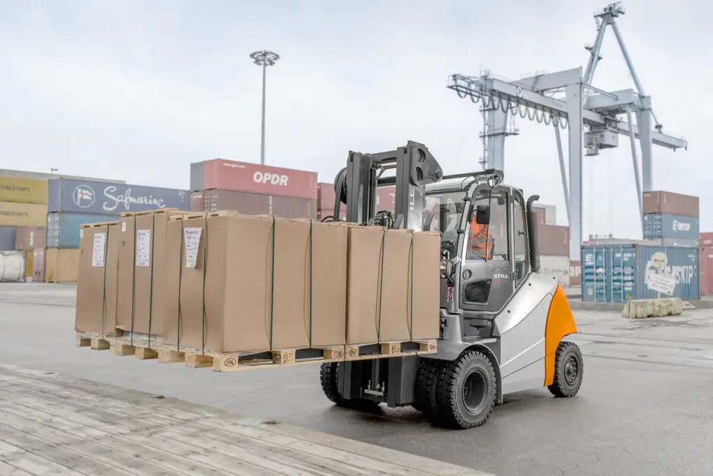 STILL RX 70 serisi çift ön lastikli dizel forklift konteyner limanında büyük koli yüklü paletleri taşırken